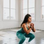 스쿼트할때 허리, 허벅지만 아프다면? a woman squatting on the floor in a gym