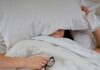 수면의 질이 건강을 좌우한다…숙면을 위한 생활습관의 중요성 person lying on bed while covering face with pillow and holding eyeglasses